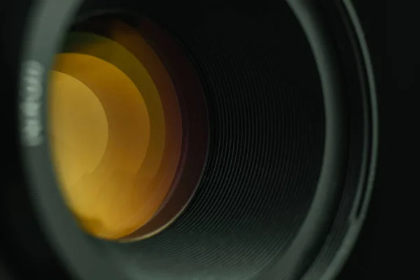 黒い背景にガラスの黄色の光を持つ美しいカメラレンズ — ストック写真