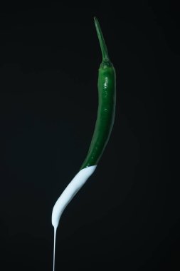 Siyah bir arka planda taze yeşil biber beyaz boya damlama. Yaratıcı poster.
