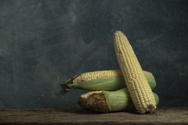 Eski bir meşe ahşap masa ve güzel gri duvar arka planda taze tatlı Mısır.