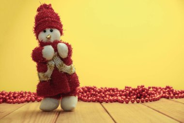 Güzel Noel baubles kardan adam kırmızı ahşap masa ve sarı arka plan üzerinde Noel Baba giyinmiş.