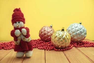 Güzel Noel baubles kardan adam kırmızı ahşap masa ve sarı arka plan üzerinde Noel Baba giyinmiş.