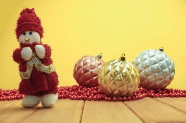 Güzel Noel baubles kardan adam kırmızı ahşap masa ve sarı arka plan üzerinde Noel Baba giyinmiş.