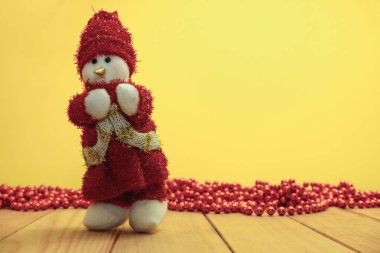Güzel Noel baubles kardan adam kırmızı ahşap masa ve sarı arka plan üzerinde Noel Baba giyinmiş.
