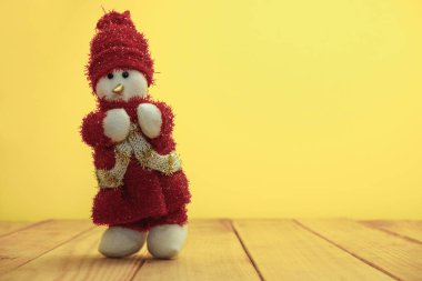 Güzel Noel baubles kardan adam kırmızı ahşap masa ve sarı arka plan üzerinde Noel Baba giyinmiş.