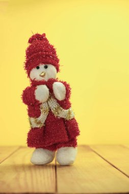 Güzel Noel baubles kardan adam kırmızı ahşap masa ve sarı arka plan üzerinde Noel Baba giyinmiş.