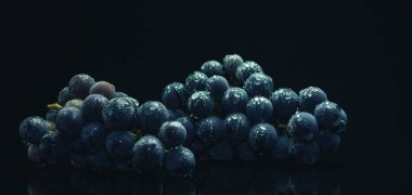 Siyah cam masa ve koyu arka plan üzerinde taze asma mavi üzüm