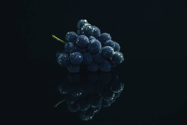 Один свежий виноград на черном стеклянном столе и темном фоне
