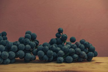 Kırmızı ahşap masa ve kırmızı duvar arka plan üzerinde güzel şarap menekşe üzüm.