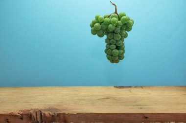 Kahverengi ahşap masa ve mavi duvar arka plan üzerinde güzel taze beyaz asma üzüm.