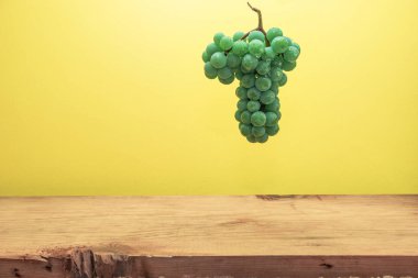 Kahverengi ahşap masa ve sarı duvar arka plan üzerinde güzel taze beyaz asma üzüm.