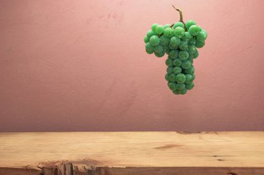 Kahverengi ahşap masa ve koyu kırmızı duvar arka plan üzerinde güzel taze beyaz asma üzüm.