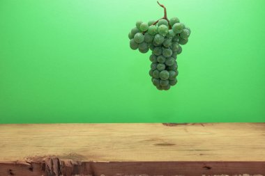 Kahverengi ahşap masa ve yeşil duvar arka plan üzerinde güzel taze beyaz asma üzüm.