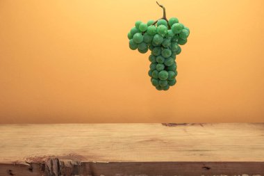 Kahverengi ahşap masa ve turuncu duvar arka plan üzerinde güzel taze beyaz asma üzüm.