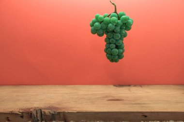 Kahverengi ahşap masa ve kırmızı arka plan üzerinde güzel taze beyaz asma üzüm.