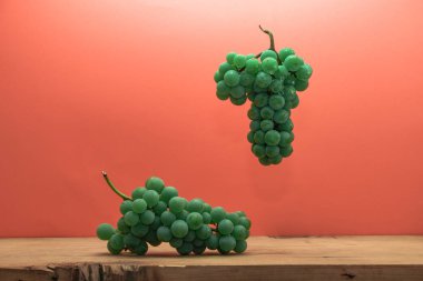 Kahverengi ahşap masa ve kırmızı arka plan üzerinde güzel taze beyaz asma üzüm.