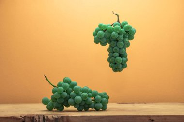 Kahverengi ahşap masa ve turuncu duvar arka plan üzerinde güzel taze beyaz asma üzüm.