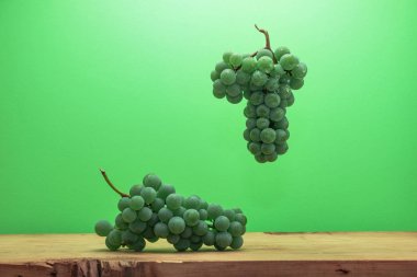 Kahverengi ahşap masa ve yeşil duvar arka plan üzerinde güzel taze beyaz asma üzüm.