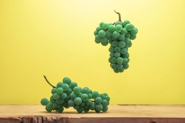 Kahverengi ahşap masa ve sarı duvar arka plan üzerinde güzel taze beyaz asma üzüm.
