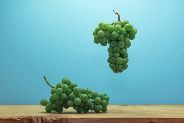 Kahverengi ahşap masa ve mavi duvar arka plan üzerinde güzel taze beyaz asma üzüm.