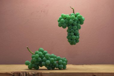 Kahverengi ahşap masa ve koyu kırmızı duvar arka plan üzerinde güzel taze beyaz asma üzüm.