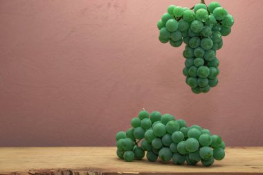 Kahverengi ahşap masa ve koyu kırmızı duvar arka plan üzerinde güzel taze beyaz asma üzüm.