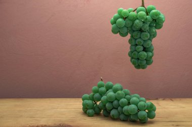 Kahverengi ahşap masa ve koyu kırmızı duvar arka plan üzerinde güzel taze beyaz asma üzüm.