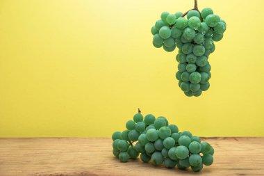 Kahverengi ahşap masa ve sarı duvar arka plan üzerinde güzel taze beyaz asma üzüm.