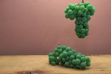 Kahverengi ahşap masa ve koyu kırmızı duvar arka plan üzerinde güzel taze beyaz asma üzüm.