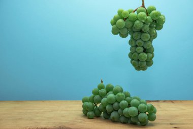 Kahverengi ahşap masa ve mavi duvar arka plan üzerinde güzel taze beyaz asma üzüm.