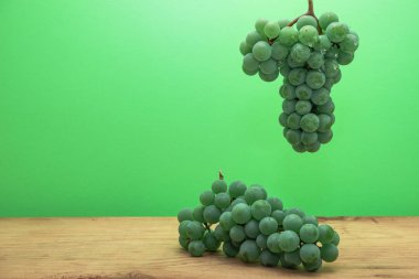 Kahverengi ahşap masa ve yeşil duvar bavkground üzerinde güzel taze beyaz asma üzüm.