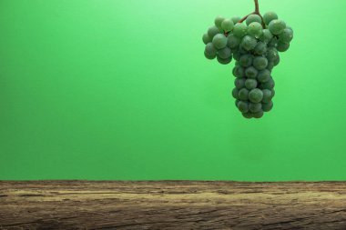 Eski bir meşe ahşap masa ve yeşil duvar arka plan üzerinde güzel taze beyaz asma üzüm.