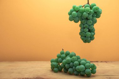 Kahverengi ahşap masa ve turuncu duvar arka plan üzerinde güzel taze beyaz asma üzüm.