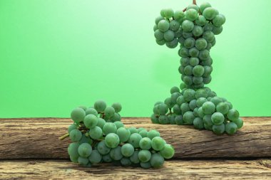 Eski bir meşe ahşap masa ve yeşil duvar arka plan üzerinde güzel taze beyaz asma üzüm.