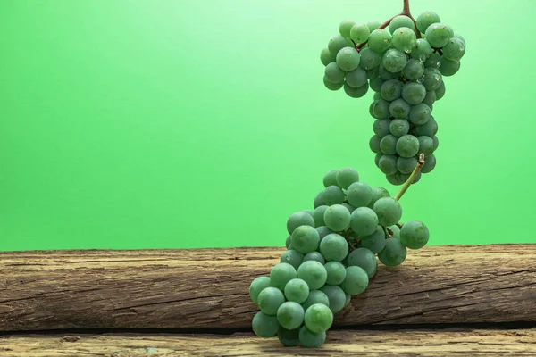 Eski bir meşe ahşap masa ve yeşil duvar arka plan üzerinde güzel taze beyaz asma üzüm.