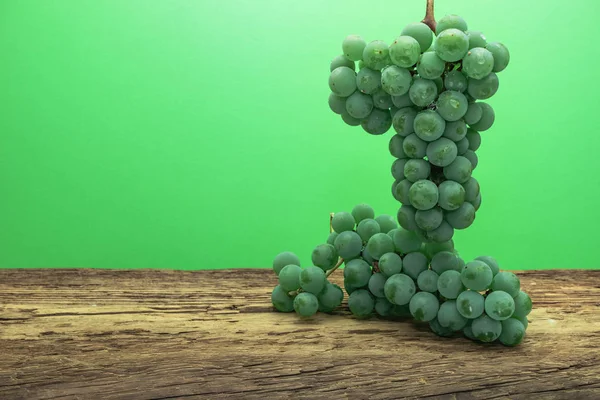 Eski bir meşe ahşap masa ve yeşil duvar arka plan üzerinde güzel taze beyaz asma üzüm.