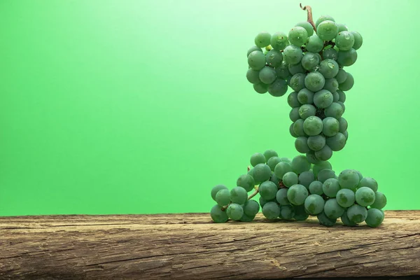 Eski bir meşe ahşap masa ve yeşil duvar arka plan üzerinde güzel taze beyaz asma üzüm.