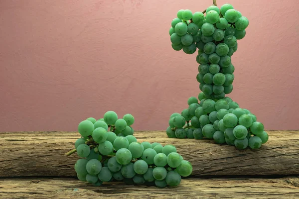 Eski bir meşe ahşap masa ve koyu kırmızı duvar arka plan üzerinde güzel taze beyaz asma üzüm.