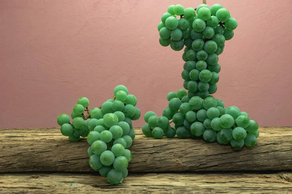 Eski bir meşe ahşap masa ve koyu kırmızı duvar arka plan üzerinde güzel taze beyaz asma üzüm.