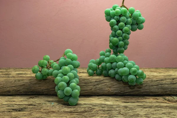 Eski bir meşe ahşap masa ve koyu kırmızı duvar arka plan üzerinde güzel taze beyaz asma üzüm.