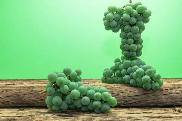 Eski bir meşe ahşap masa ve yeşil duvar arka plan üzerinde güzel taze beyaz asma üzüm.