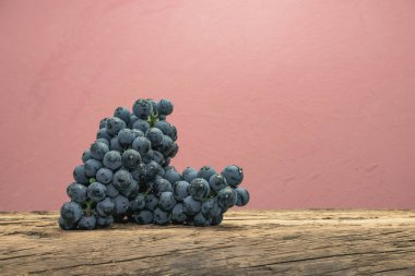 Eski bir meşe ahşap masa ve kırmızı duvar arka plan üzerinde güzel şarap Kadarka üzüm.