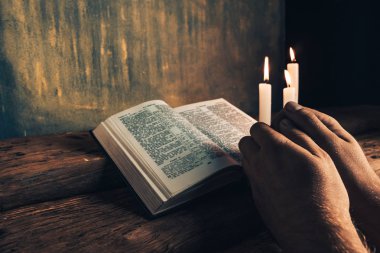 Eski bir meşe ahşap masa ve altın duvar backgroud üzerinde İncil okuma bir masada oturan adam kapatın