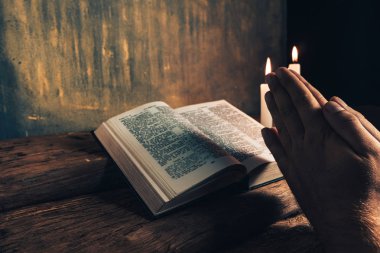 Eski bir meşe ahşap masa ve altın duvar backgroud üzerinde İncil okuma bir masada oturan adam kapatın