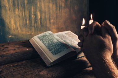 Eski bir meşe ahşap masa ve altın duvar backgroud üzerinde İncil okuma bir masada oturan adam kapatın