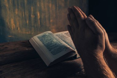 Eski bir meşe ahşap masa ve altın duvar backgroud üzerinde İncil okuma bir masada oturan adam kapatın