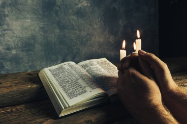 Eski bir meşe ahşap masa ve gri duvar backgroud üzerinde İncil okuma bir masada oturan adam kapatın