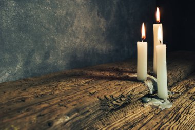 Eski bir meşe ahşap masa ve koyu gri duvar arka plan üzerinde güzel yanmış mumlar kapatın. 