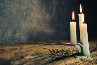 Eski bir meşe ahşap masa ve koyu gri duvar arka plan üzerinde güzel yanmış mumlar kapatın. 