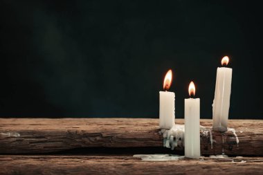 Eski bir meşe ahşap masada güzel üç beyaz yanmış mumlar. Mavi ve kırmızı dumanArka Plan