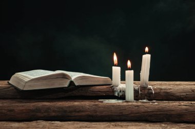 Güzel açık İncil ve eski bir meşe ahşap masada mumlar yandı. Dumanın arka planı.
